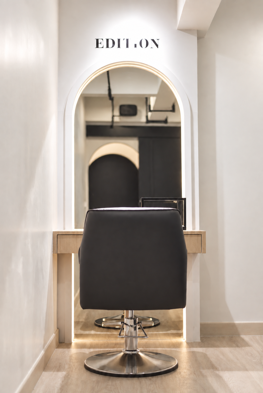 Private room with a single styling chair and arch mirror beneath the EDITION sign