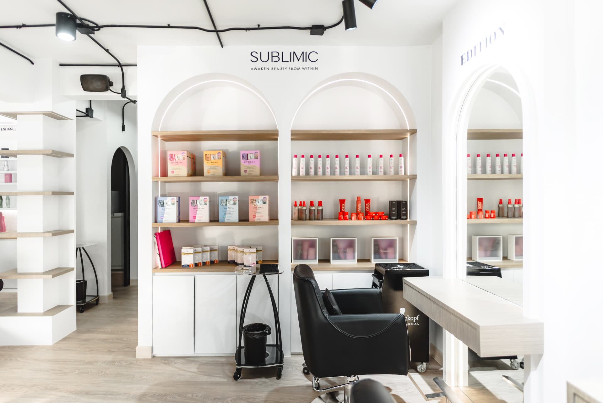 Styling chair and arch mirror beside the SUBLIMIC product shelves at EDITION Salon
